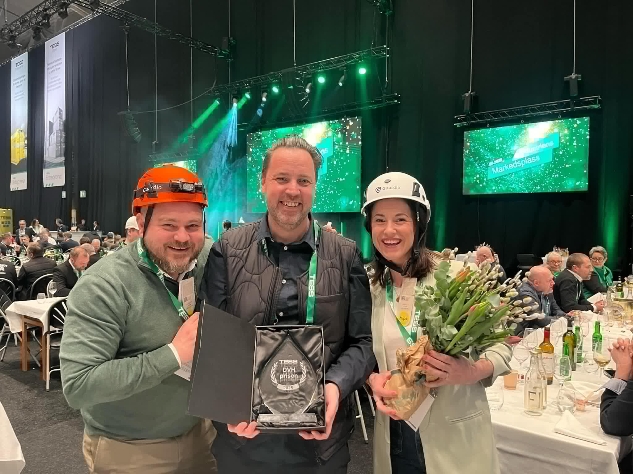 Tre medarbejdere fra Båstadgruppen i sikkerhedshjelme holder DVH-prisen op.